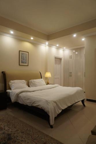 a bedroom with a large bed with white sheets and a lamp at Wisteria Cottage in Dunga Gali