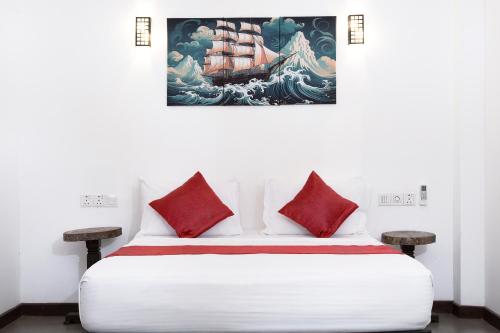 a white bed with red pillows and a painting on the wall at Luminara Sky Lounge with Pool near Ahangama Beach in Ahangama