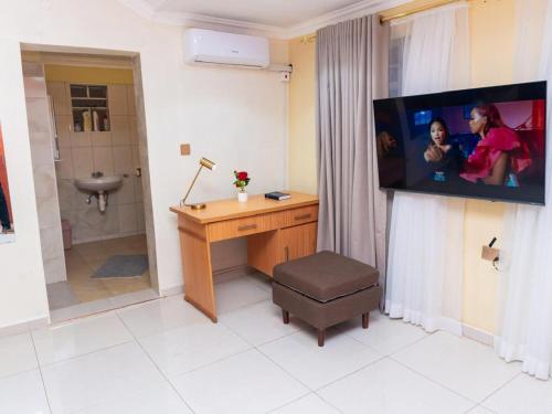 a bathroom with a desk and a tv on a wall at JAC Tilama BNB in Blantyre