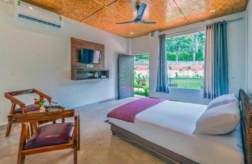 a bedroom with a bed and a desk and a window at Earavat Resort in Rāmnagar