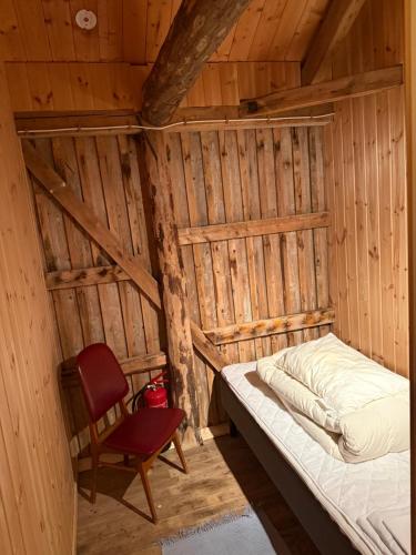a bed and a chair in a wooden room at Skjellfjord cabin in Skjelfjord