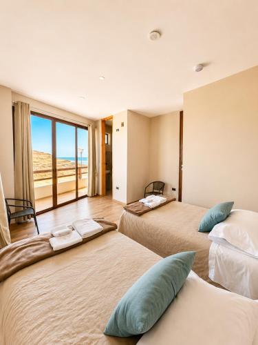 two beds in a room with a view of the ocean at Family Surf Chicama in Puerto Chicama