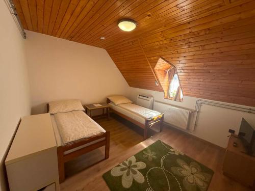 a room with two beds and a wooden ceiling at Családfa Vendégház in Ságvár