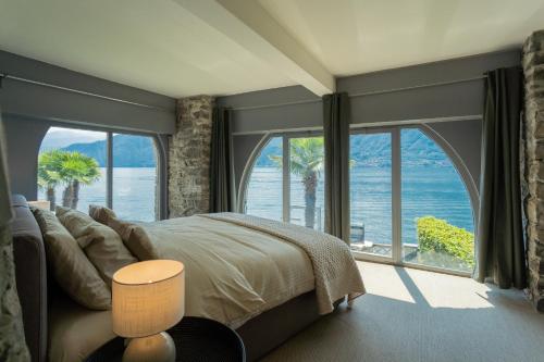 a bedroom with a large bed and large windows at Villa Sasso On Lake Como by Rent All Como in Sala Comacina