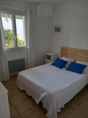 a bedroom with a large white bed with blue pillows at Les mimosas in Collioure