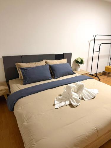 a large bed with white sheets and blue pillows at Breezy 1BR Near BTS Udomsuk in Amphoe Phra Khanong