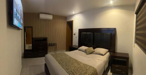 un dormitorio con una cama grande y un televisor de pantalla plana en Hotel MAC7, en Aguascalientes