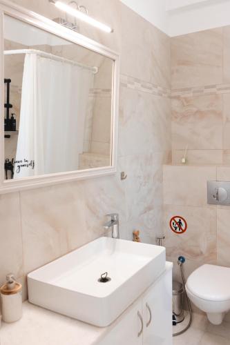 a bathroom with a white sink and a toilet at Orion Sea View Studio in Parasporos