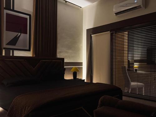 a bedroom with a bed and a window with a chair at Private & Serene Golf View Apt Phase 7 in Rawalpindi