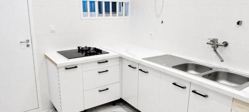 a white kitchen with white cabinets and a sink at Appartement moderne avec balcon in Lomé
