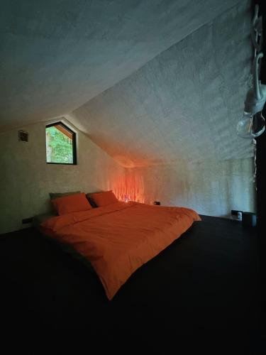 a bedroom with a large orange bed with a window at River Nest Tiny House in Iecava