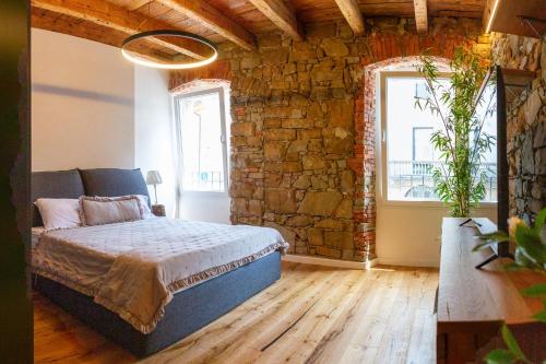a bedroom with a bed and a brick wall at Stevoski Rooms - Modern Comfort in a Historic Stone House in Cormòns