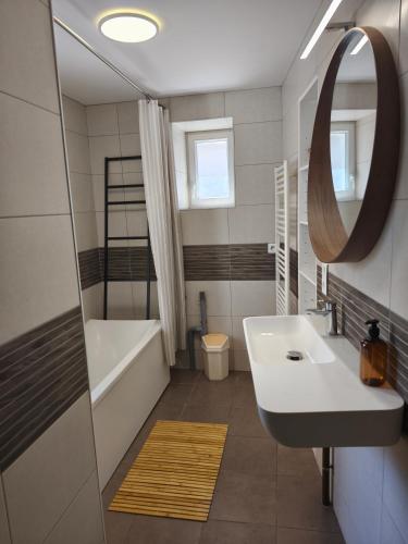 a bathroom with a sink and a tub and a mirror at NEW! Appartement PrixMalin 1 à 7 personnes in Champagnole