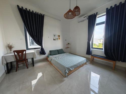 a bedroom with a bed and a desk and windows at Nhi Homestay Phòng đơn 1 in Rạch Giá