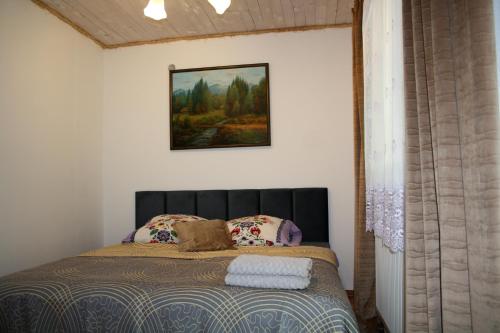 a bedroom with a bed with a picture on the wall at Dom w Bieszczadach 10 osobowy in Wołkowyja