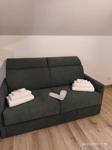 a green couch with two pairs of slippers on it at L'appartement à la ferme in Béthune