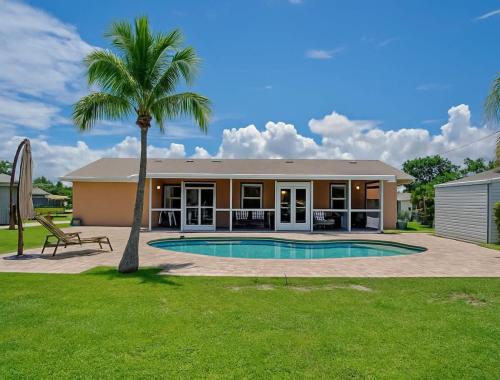 a house with a palm tree and a swimming pool at 3BR Pool Villa on Golf Course Huge Yard & Games in Wellington