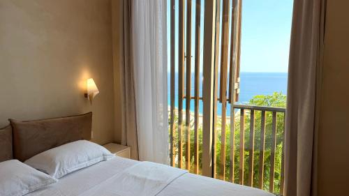 a bedroom with a bed and a view of the ocean at Green Coast Pearl Suites Apartments Palase in Palasë