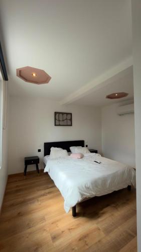 a bedroom with a large white bed and wooden floors at Sauna spa in Rouen