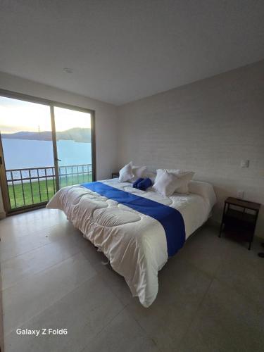 a large bed in a room with a large window at Nuevos departamentos en Valle de Bravo in Valle de Bravo