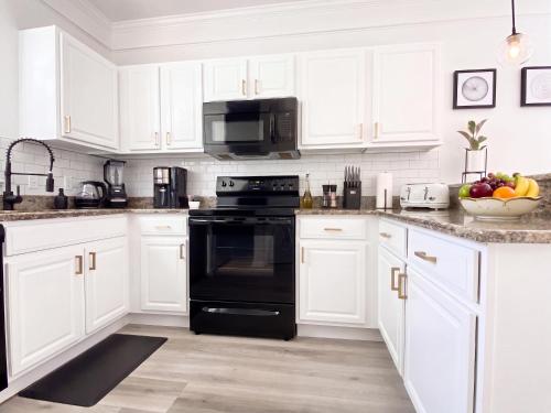 a kitchen with white cabinets and black appliances at Sanctuary at Oaks - Full Kitchen , Near I75 in Gainesville