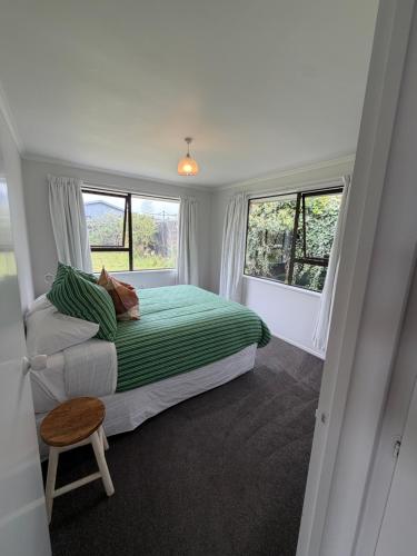 a bedroom with a bed and two windows at Esplanade Stay in Kaikoura