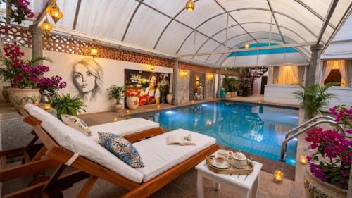 a swimming pool with chairs and a couch next to a pool at De Majestic Grand Villa in Auroville