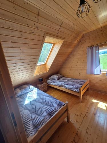 a bedroom with two beds in a log cabin at Łąkowe Zacisze - Kozin in Bogaczewo