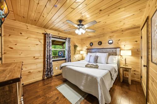 a bedroom in a log cabin with a bed and a ceiling fan at Heavenly Daze Amazing Mountain View, Hot Tub, Game Room! in Sevierville