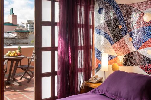 a room with a bed and a balcony with a table at Hotel Casa Deco in Bogotá
