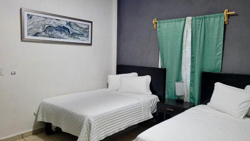 ein Zimmer mit zwei Betten und einem grünen Vorhang in der Unterkunft Hotel Jasli Escárcega in Escárcega