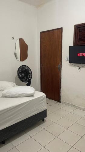 a room with a bed and a door and a television at Pousada Só Alegria in Fortaleza