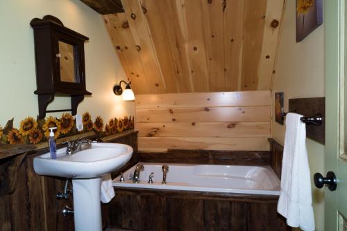 a bathroom with a sink and a bath tub at Natur'Eau Chalets & Spa in Mandeville