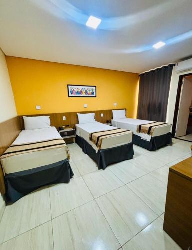 a room with two beds and a yellow wall at Boulevard Park Hotel in São Luís