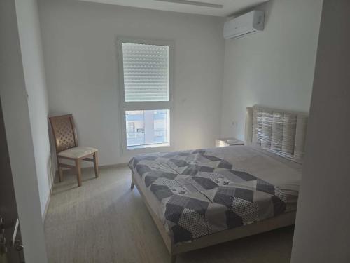 a bedroom with a bed and a chair and a window at rental per night in Nabeul