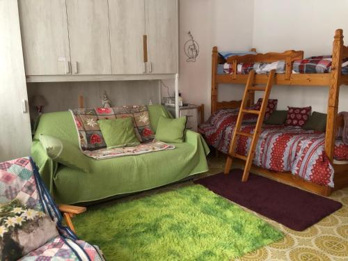 a living room with a green couch and a bunk bed at L'oasi dei larici - Montoso in Bagnolo Piemonte