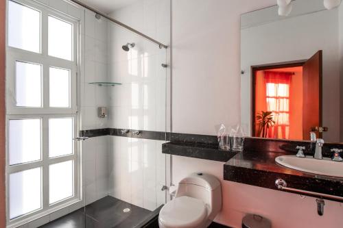 a bathroom with a toilet and a sink and a mirror at Hotel Casa Deco in Bogotá