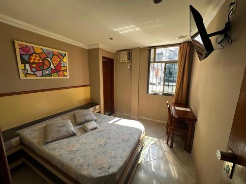 a small bedroom with a bed and a window at Grande Hotel in Duque de Caxias