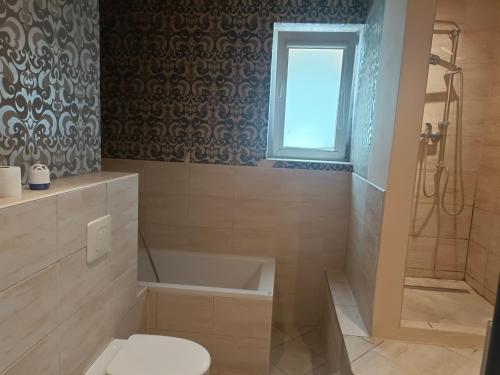 a bathroom with a tub and a toilet and a window at Hostel Tet6 in Gdynia