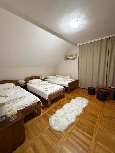 a room with four beds and a white rug at Balkan 024 in Subotica
