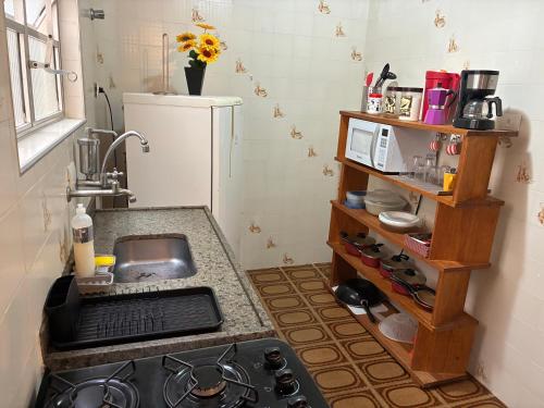 a kitchen with a stove and a sink and a refrigerator at Apartamento Brisa Do Mar em Peruíbe in Peruíbe