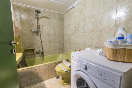 a bathroom with a washing machine and a tub at Varkiza Beach Summerhouse-Athens Riviera in Vari