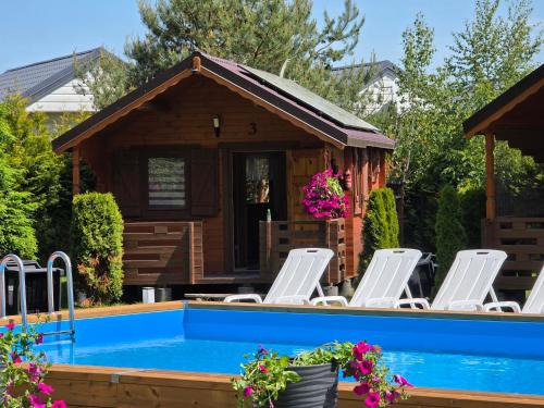 a pool with lounge chairs and a house at Arcada in Jarosławiec