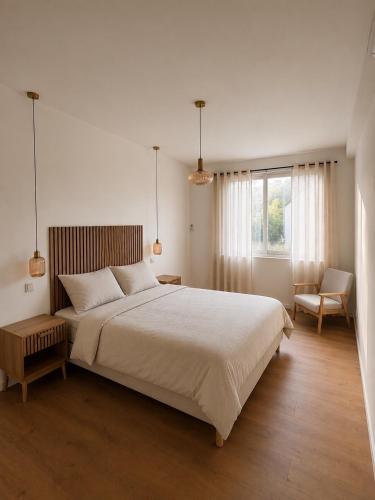 a bedroom with a large white bed and a chair at Le Comptoir du Relais in Beine