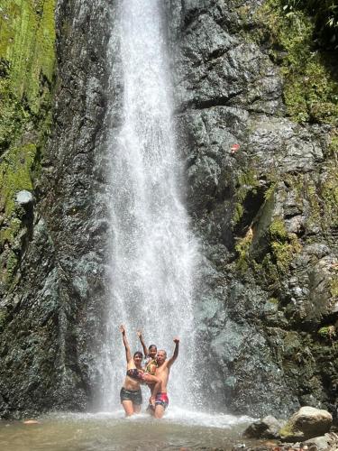 two people standing in the water in front of a waterfall at Cascada Sagrada in Pijao