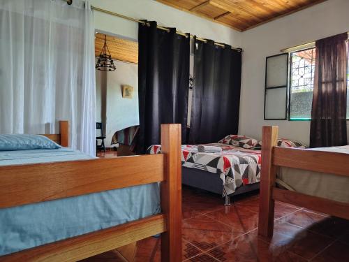 a bedroom with two beds and a window with curtains at Riveras Del Magdalena in Honda