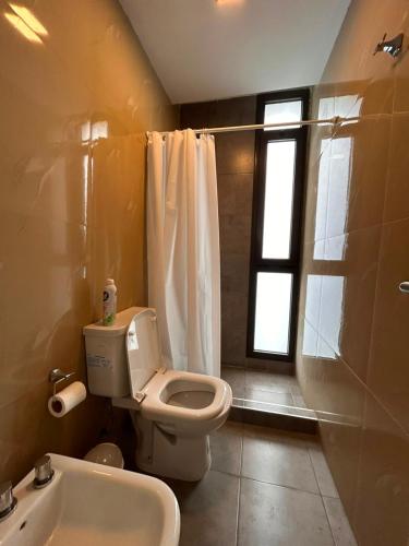 a bathroom with a toilet and a sink and a window at Emma in Villa Carlos Paz