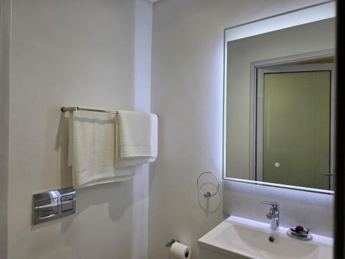 a bathroom with a sink and a mirror and towels at Kingsley at 1 on Albert in Cape Town