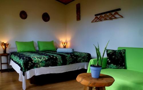 a room with a bed with green sheets and a table at Fare Atihau Vairao in Matiti