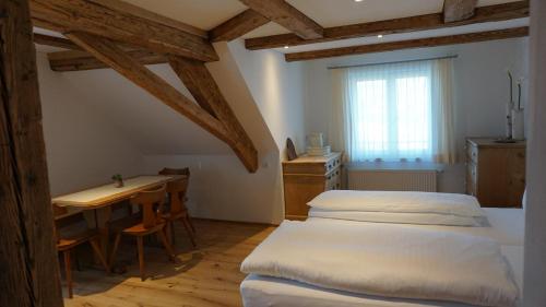 a bedroom with two beds and a table and a window at Waldrast Bed & Breakfast in Batschuns